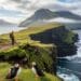 Person hiking along a dramatic Faroe Islands coastline with puffins in the foreground