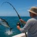 A fisherman reeling in a large tuna during a deep-sea fishing trip on a sunny day