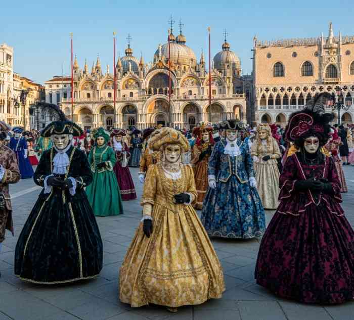 Tourists and performers wearing traditional Venetian masks during Venice Carnival in Italy